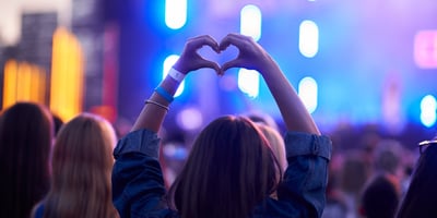 Person at a music concert making a heart with their hands