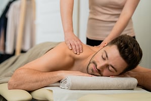 A man on a massage table with hands massaging his back