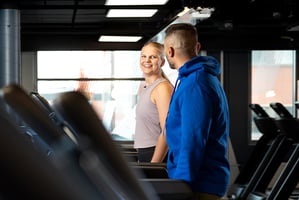 A woman and a man exercising on treadmills