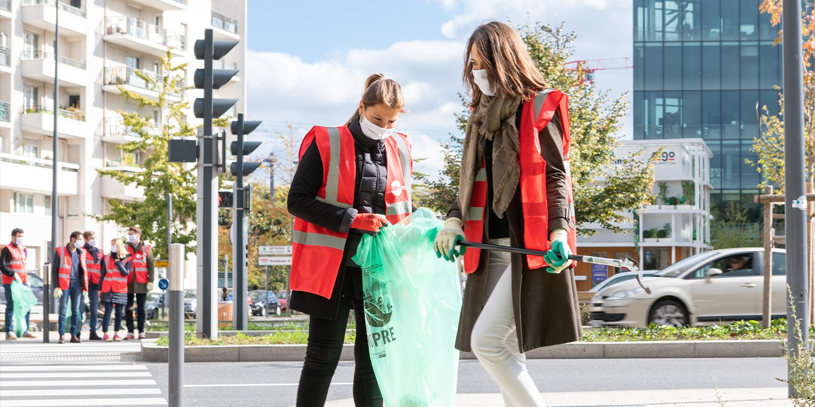Young women wearing red vests and collecting trash