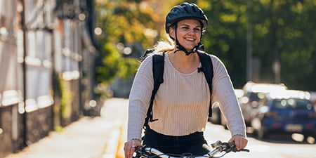  A smiling young woman pedals the streets of Helsinki on a company bicycle