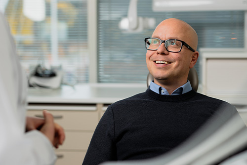 A man with glasses is sitting in a doctor's chair